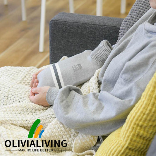 Adult using an OliviaLiving Classic 2L striped-cover hot water bottle on a sofa