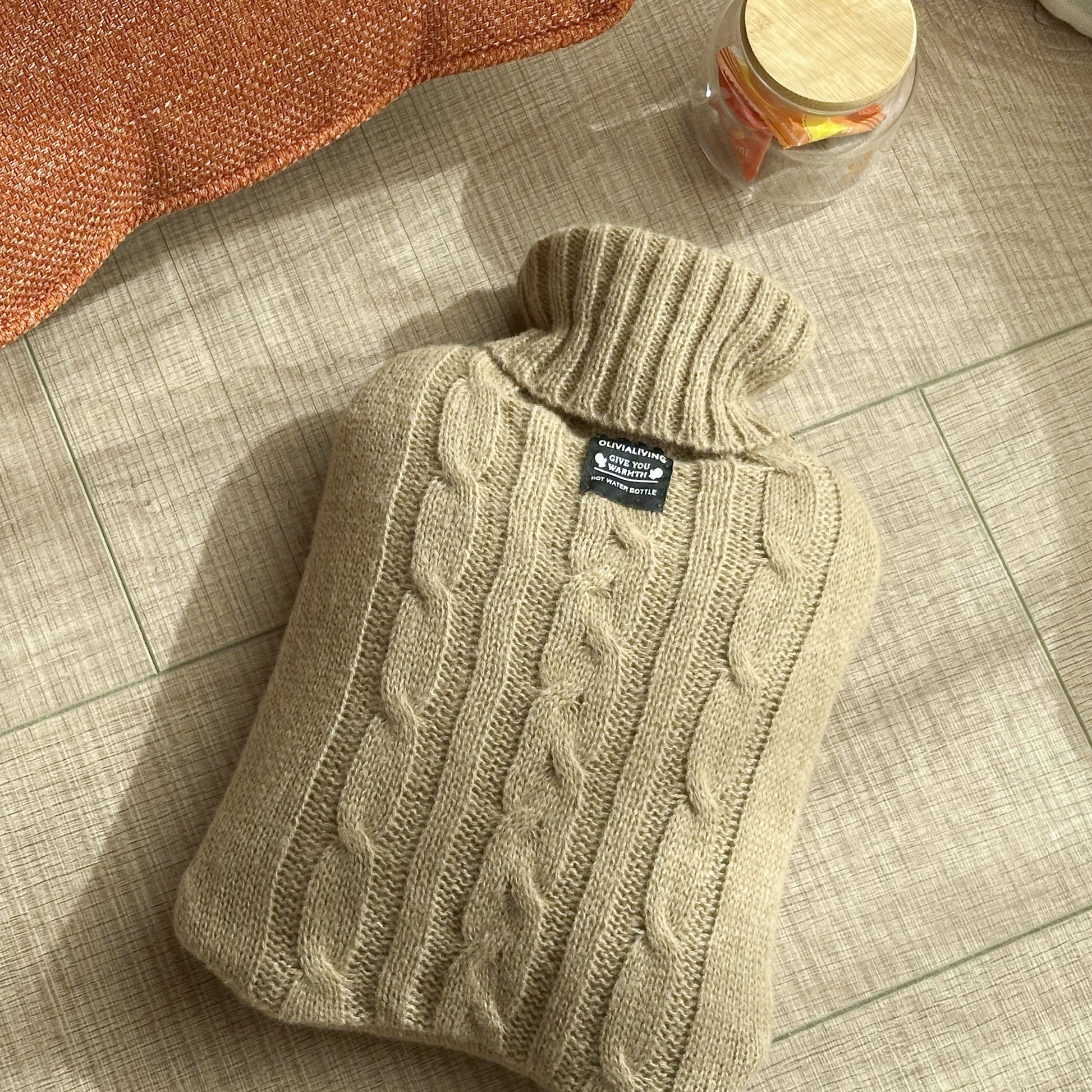 OliviaLiving 2L hot water bottle with coffee cable-knit cover in a warm home setting