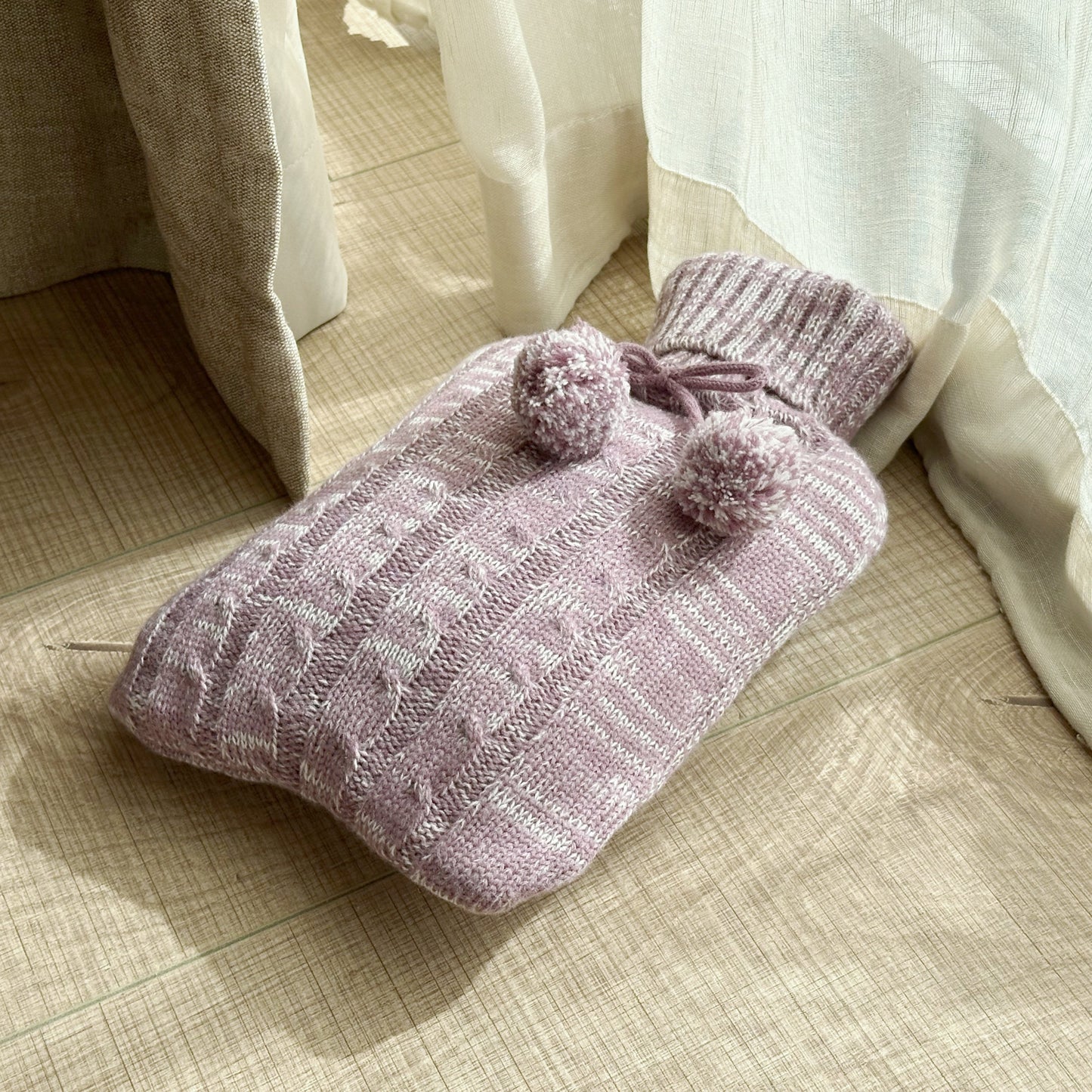 OliviaLiving pink melange 2L hot water bottle with pom-pom knit cover in soft window light